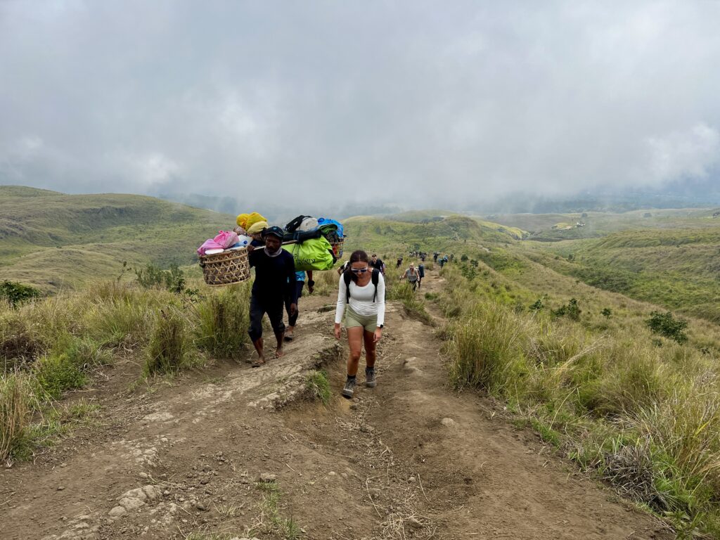 Hiking Mount Rinjani, Lombok, Indonesia. Hikers along the upper path between POS1 and POS2 along the tops of rolling hills in a grassland savannah.