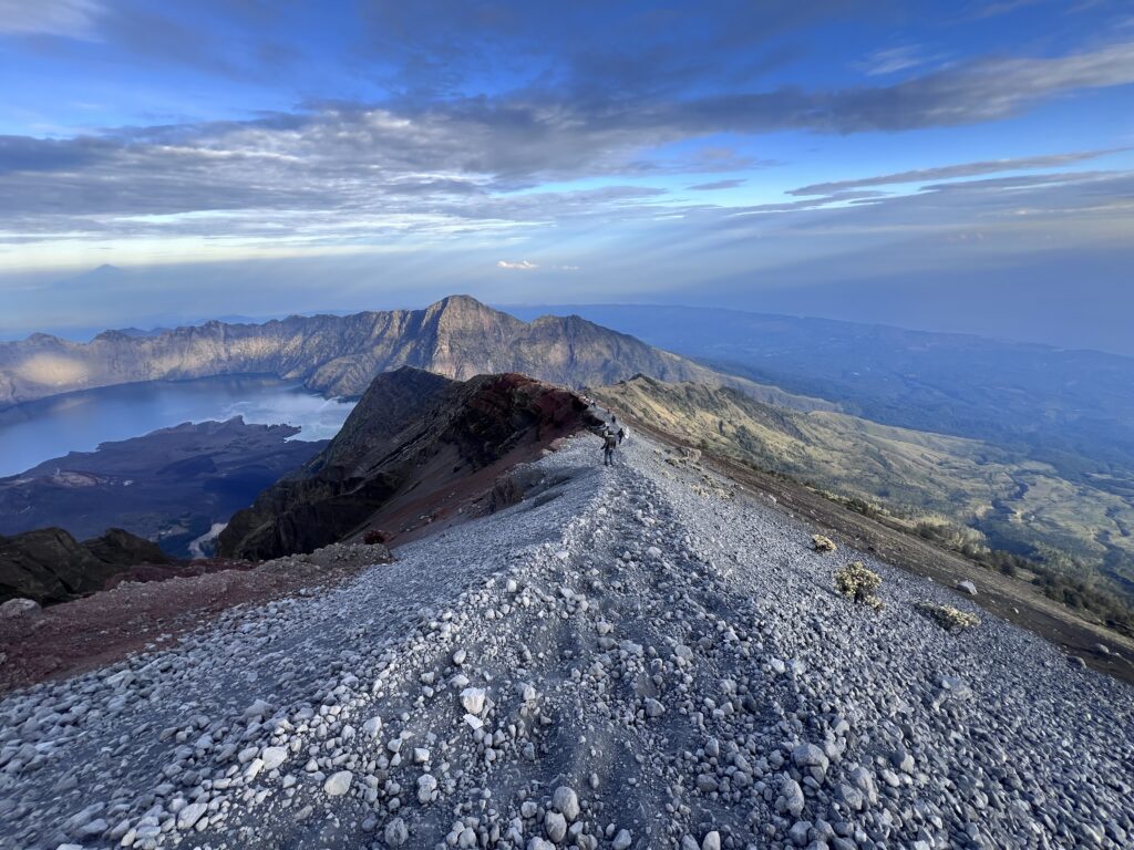 Hiking Mount Rinjani, Lombok, Indonesia. Hikers allong the narrow path over a scree field, along the volcanic ridge of mount Rinjania in the early morning descending from the summit. 